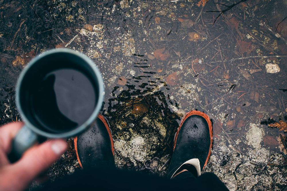 Hands holding a mug of hot coffee outdoors