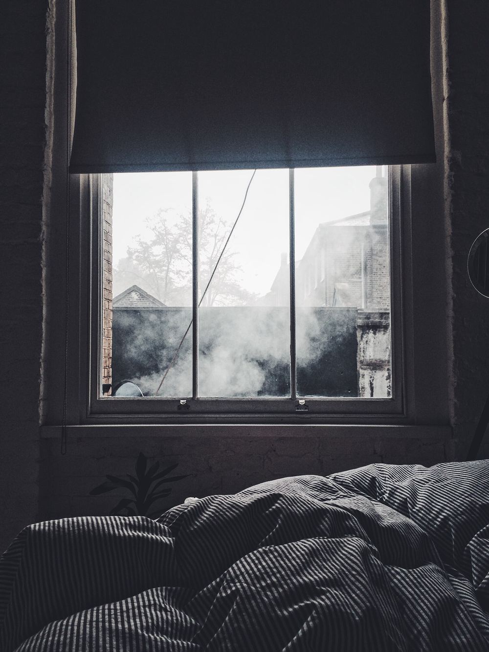 Bedroom with a large window looking into fog